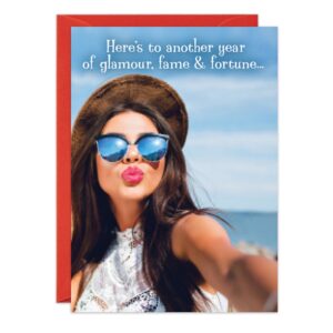A woman in sunglasses and a hat takes a selfie at the beach, puckering her lips. Above her reads: “Here’s to another year of glamour, fame & fortune...” A red envelope peeks out behind the 8882.jpg Glamour Birthday Card.